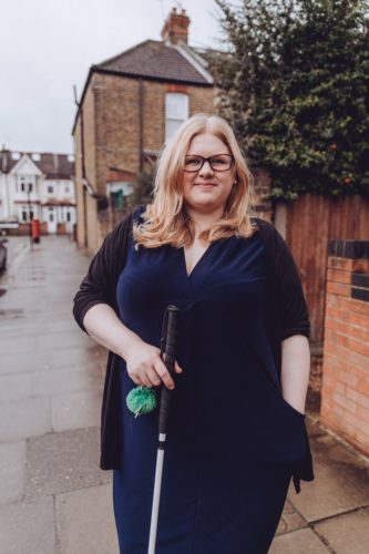 Amy standing outside in a blue dress with her cane